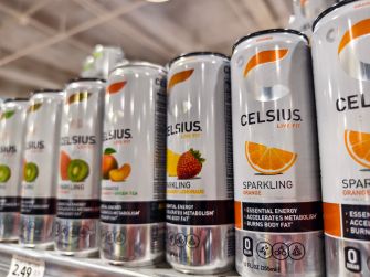 Celsius sparkling energy drink cans displayed on a store shelf, including flavors labeled “Burns Body Fat” and “Accelerates Metabolism.”