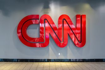 Red CNN logo mounted on a wall above a tiled floor.