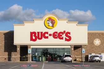 Buc-ee’s storefront with red signage, beaver mascot emblem, and parked cars outside.