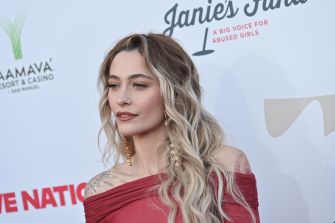 Paris Jackson poses in a red off-the-shoulder dress at a red-carpet event.