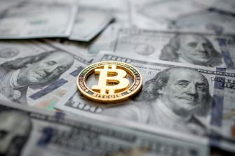 A Bitcoin coin placed on top of US currency notes.