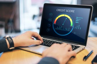A person analyzing a credit score on a laptop screen displaying a gauge and metrics.