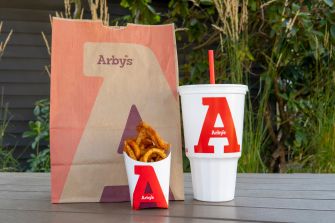 Packaging of Arby’s fries and a drink on a table, highlighting the brand's logo.