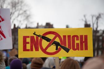 Protest sign with a crossed-out assault rifle and the word "ENOUGH" during a demonstration against gun violence.