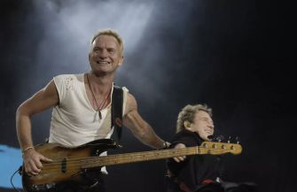 Sting performing on stage with an accompanying musician.