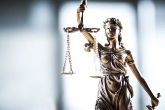 A bronze statue of Lady Justice holding scales and a sword, symbolizing the legal system and justice.
