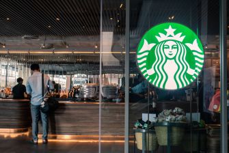 Image of a Starbucks store with a visible logo and a customer at the counter.