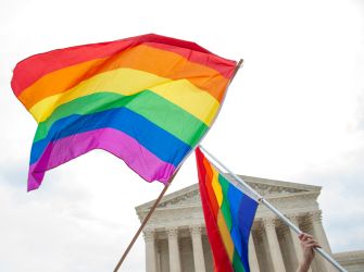Rainbow Pride flags waving in front of the U.S. Supreme Court building.