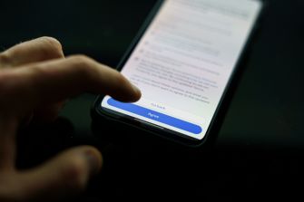 A person’s finger hovering over a smartphone screen displaying terms of service and an "Approve" button.