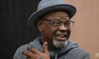Glynn Simmons smiling while speaking, wearing a gray hat and glasses, reflecting on his wrongful incarceration and recent settlement.
