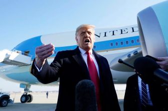 Former President Trump speaking to the press near an airplane.