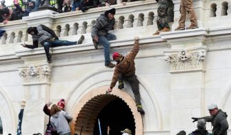 A group of individuals attempting to breach the Capitol building during the January 6 riots, showcasing various actions of climbing and navigating the structure.