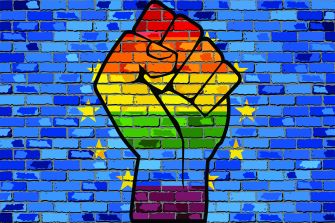Illustration of a rainbow-colored raised fist against a blue brick wall with yellow stars, symbolizing LGBT rights.