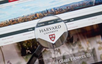 A magnifying glass focusing on the Harvard University logo displayed on a website.