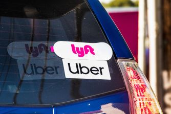 A close-up of the back of a car displaying both Uber and Lyft stickers.