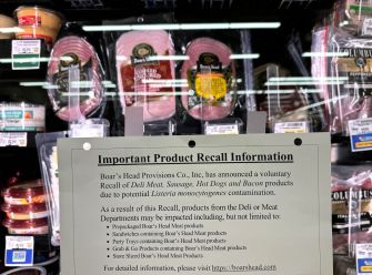Recall notice for Boar's Head products due to potential listeria contamination displayed in a supermarket deli section.