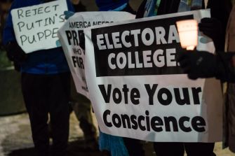 Participants holding signs advocating for the Electoral College, with messages urging voters to act according to their conscience.