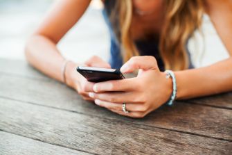 Close-up of hands using a smartphone on a wooden table