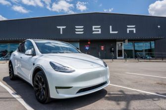 Tesla vehicle parked in front of a Tesla factory building.