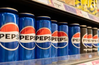 Row of Pepsi soda cans on a grocery store shelf.