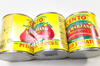 Three Cento brand San Marzano tomato cans with yellow labels arranged on a white surface