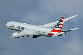 American Airlines passenger plane in flight against a cloudy sky.