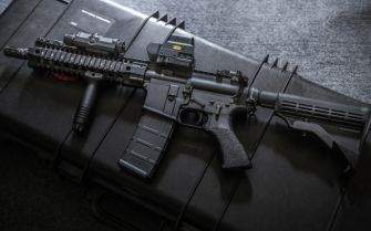 A rifle placed on a protective case, showcasing its features.