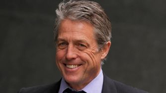 A smiling middle-aged man with gray hair, dressed in a dark suit and light shirt, poses for the camera.