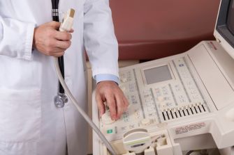 A medical professional adjusting an ultrasound machine in a clinical setting.