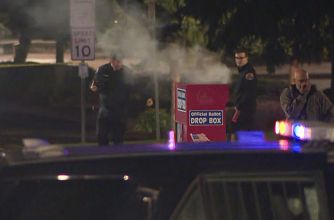 Police investigate a ballot drop box with smoke rising from it, following a reported fire incident.