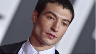 Ezra Miller at a film premiere, appearing serious and contemplative.