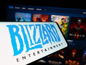 Logo of Blizzard Entertainment displayed on a smartphone with a blurred background of game titles.