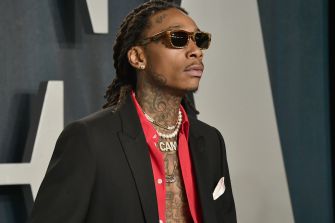 Wiz Khalifa wearing sunglasses and gold chains at a red-carpet event.