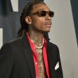 Wiz Khalifa wearing sunglasses and gold chains at a red-carpet event.