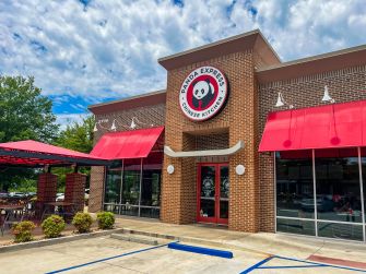 Exterior of a Panda Express restaurant with red awnings, brick facade, and panda logo.