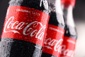 Close-up of Coca-Cola bottles with red labels reading Original Taste, covered in water droplets.