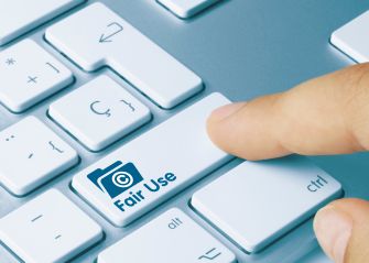 A finger pressing a keyboard key labeled "Fair Use" with an icon symbolizing copyright.