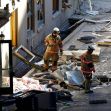 Two firefighters inspecting debris outside the Sandman Hotel after an explosion.