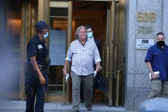 Steve Bannon exiting a building accompanied by law enforcement officers.