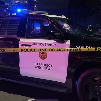 Police vehicle with caution tape reading "POLICE LINE DO NOT CROSS" and "TO PROTECT AND SERVE."