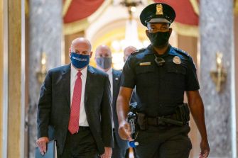 Postmaster General Louis DeJoy arriving at a congressional hearing with security personnel.