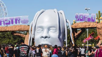 A large sculpture of a head with the text "ASTRO WORLD" displayed above, surrounded by attendees at the Astroworld music festival.