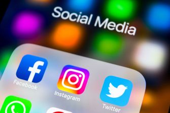 Social media apps displayed on a smartphone screen with a blurred background.