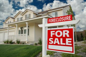 A house with a "Foreclosure" and "For Sale" sign in the front yard.