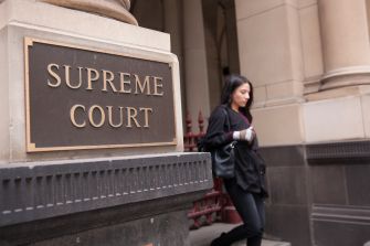 A person walking past a sign for the Supreme Court building.