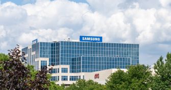 Samsung corporate building with blue glass exterior and a large Samsung sign on the roof, with trees in the foreground.