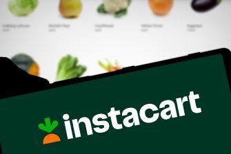 Instacart logo on a dark green sign with blurred produce in the background