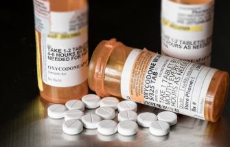 Bottles of prescription opioid medications with tablets scattered on a surface.