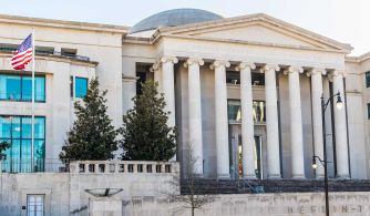 Exterior view of the Alabama Supreme Court building with the American flag in the foreground.