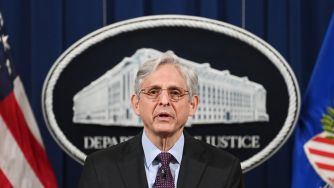 Attorney General Merrick Garland speaks at a podium with the Department of Justice seal in the background.
